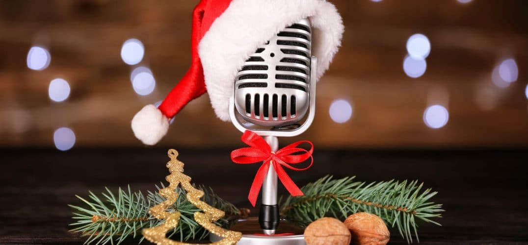 Vintage microphone wearing Santa hat next to pine boughs and chestnuts