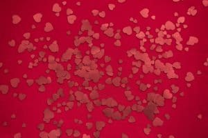 Glitter hearts scattered against a red background.